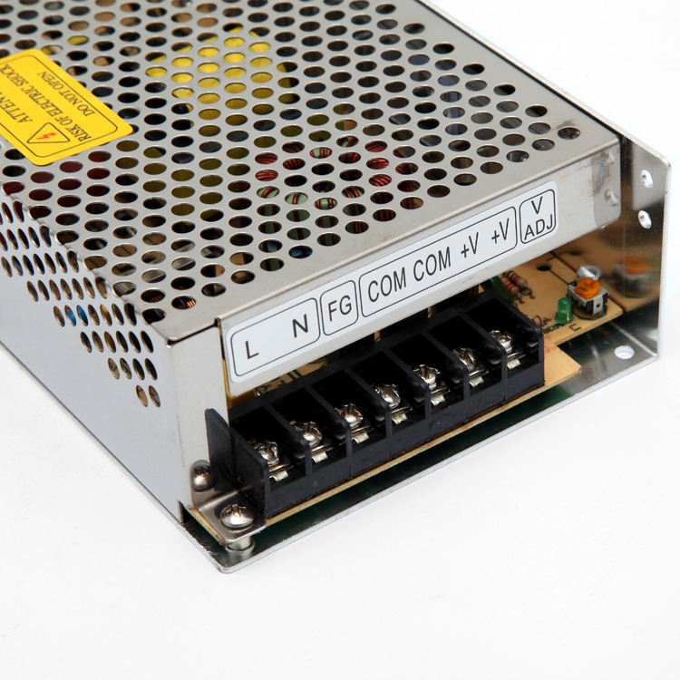 Enclosed switching power supply terminal block close-up with L, N, FG, COM and V adjustment labels